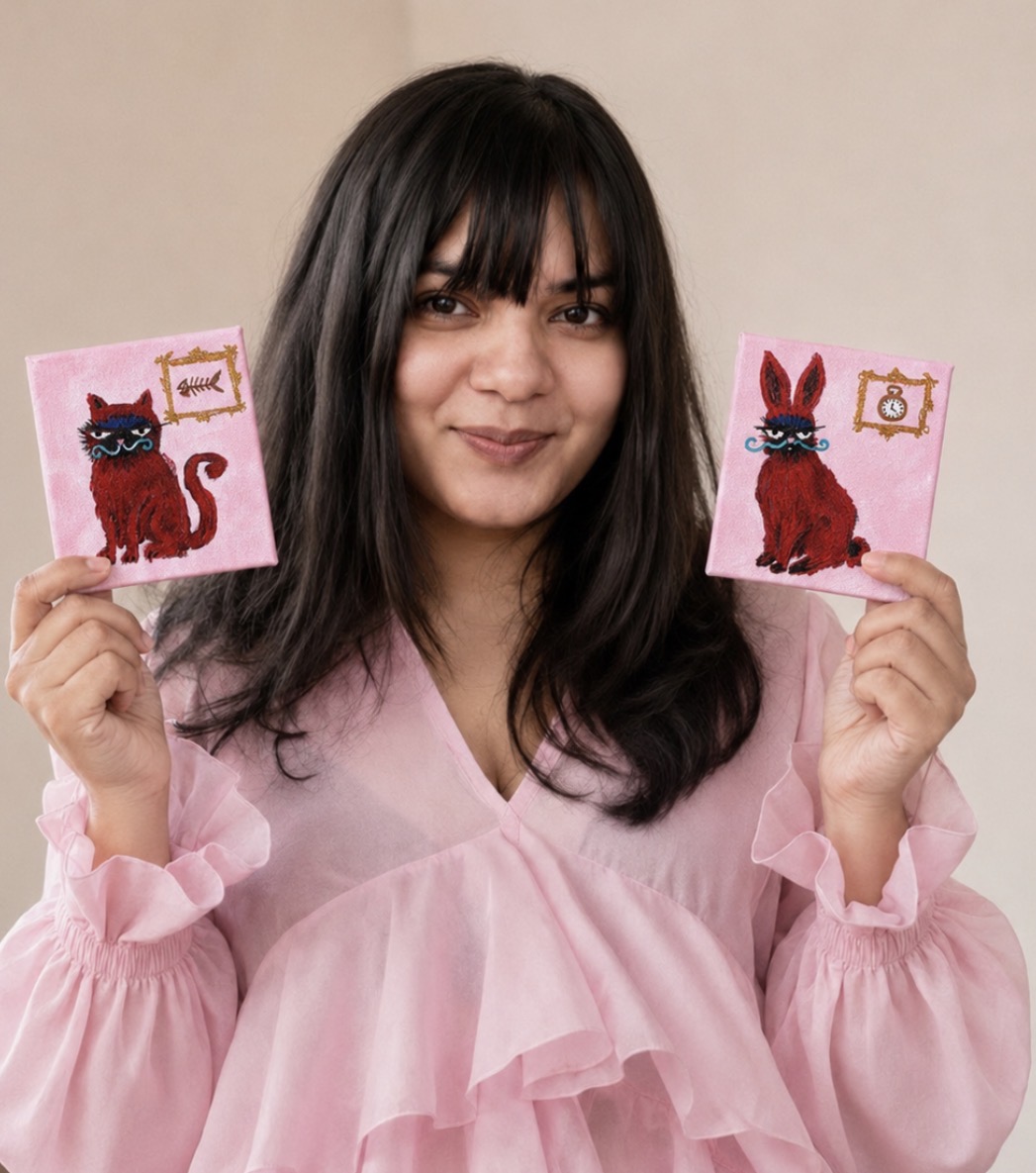 Janice Ruth Gracias holding two small original paintings